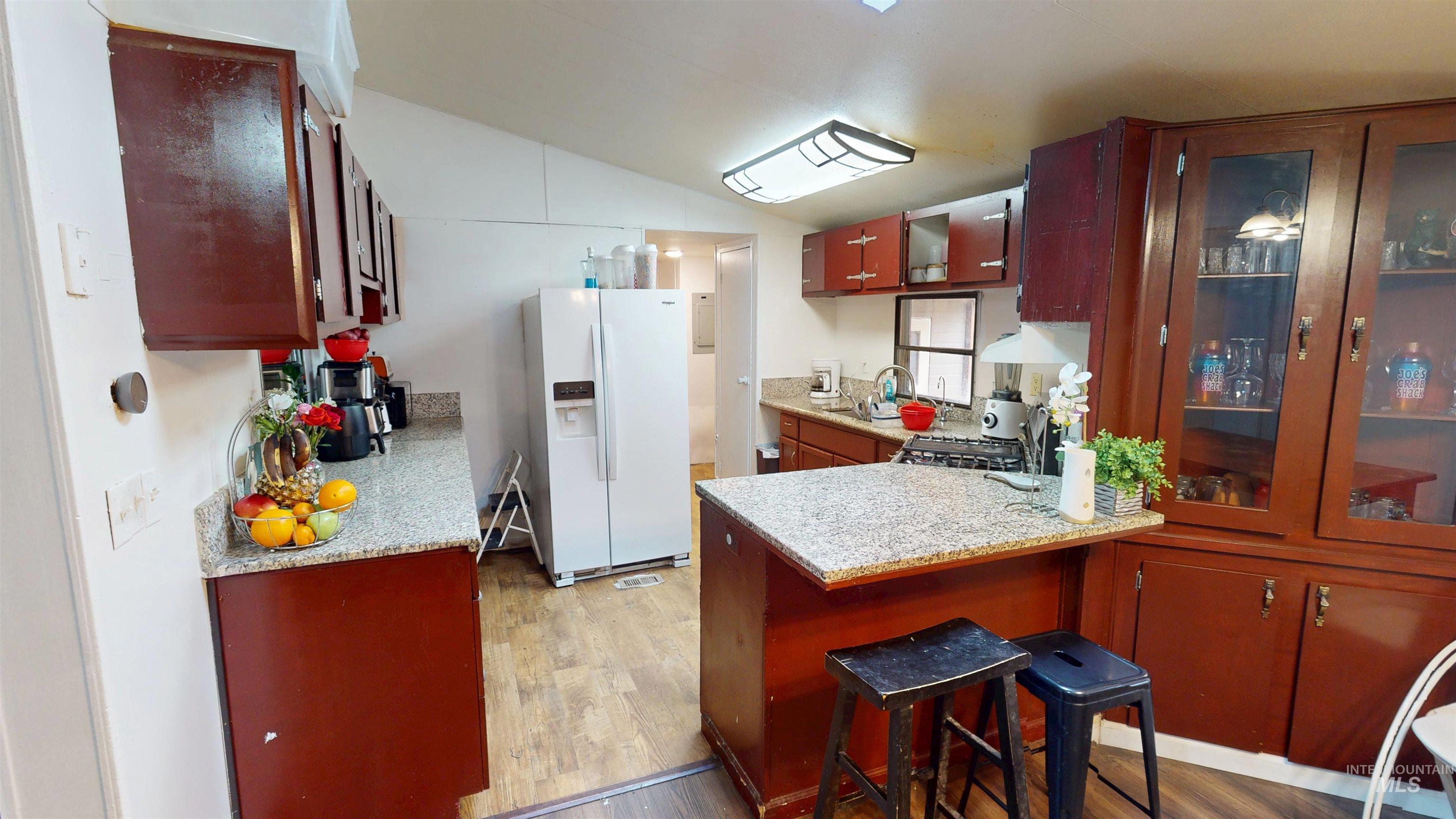 19151 Symms Road Caldwell, ID 83607 - Photo 10 of 14 Kitchen with white fridge with ice dispenser, glass insert cabinets, a peninsula, light wood finished floors, and lofted ceiling