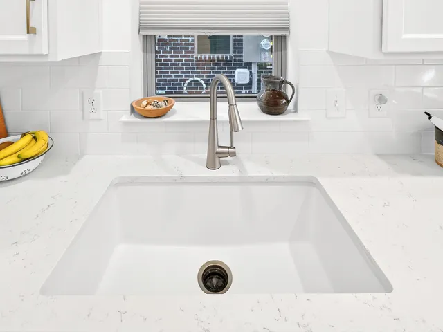a kitchen with stainless steel appliances a sink a stove and white cabinets