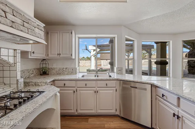 a kitchen with kitchen island a counter top space wooden floor cabinets and stainless steel appliances