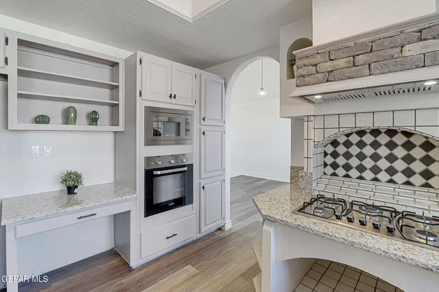 a kitchen with stainless steel appliances granite countertop a stove top oven a sink dishwasher and a refrigerator with wooden floor