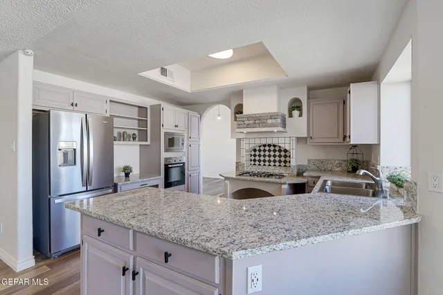 a kitchen with granite countertop a refrigerator and a sink