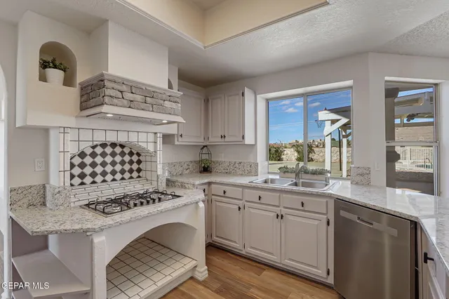 an empty room with wooden floor fire place and windows