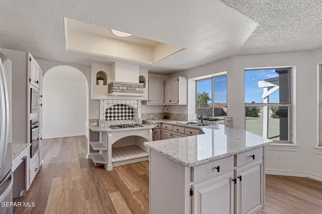 a view of an empty room with wooden floor fireplace and a window