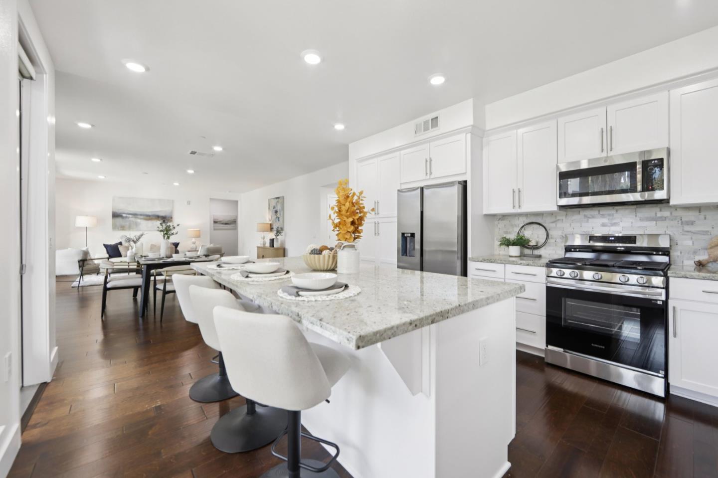 390 Riesling Avenue, Unit 21 Milpitas, CA 95035 - Photo 13 of 48 a kitchen with stainless steel appliances kitchen island granite countertop a stove a sink a microwave a refrigerator and white cabinets with wooden floor