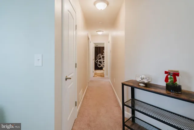 a view of a hallway to room with wooden floor and cabinet