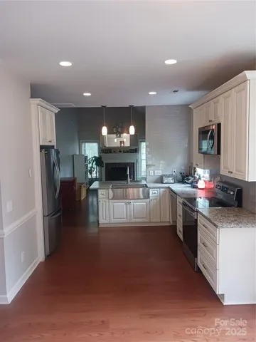 a kitchen with stainless steel appliances kitchen island granite countertop a refrigerator a stove top oven a sink and dishwasher