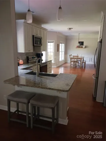 a kitchen with granite countertop a table chairs microwave and sink