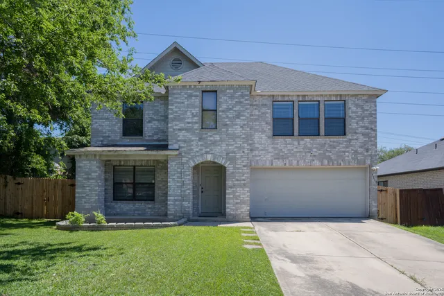 a front view of a house with a garden and trees