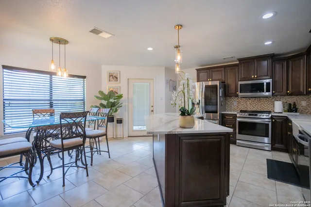 a kitchen with kitchen island granite countertop a stove a sink a oven a dining table and chairs with wooden floor