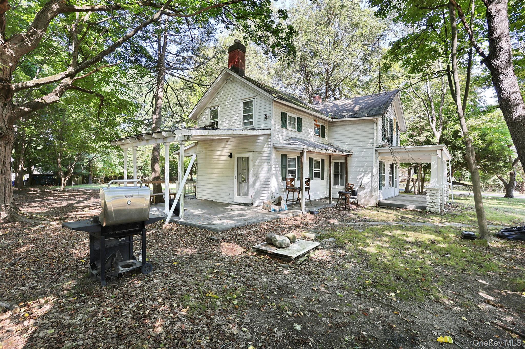 4 Bellows Lane Chestnut Ridge, NY 10952 - Photo 11 of 13 Rear view of house with a chimney, a patio area, and view of scattered trees