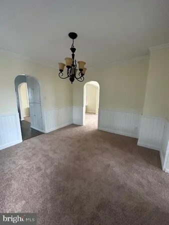 a view of a room with a hanging light and hardwood