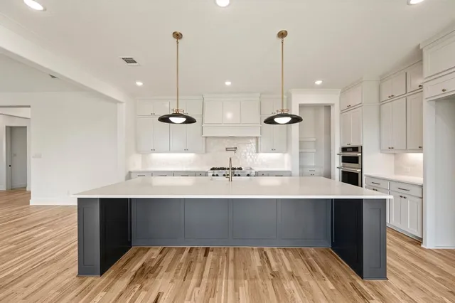 a large kitchen with kitchen island a sink stainless steel appliances and white cabinets