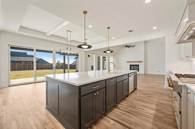 a large kitchen with stainless steel appliances granite countertop a large kitchen island a stove a sink dishwasher and a wooden floor