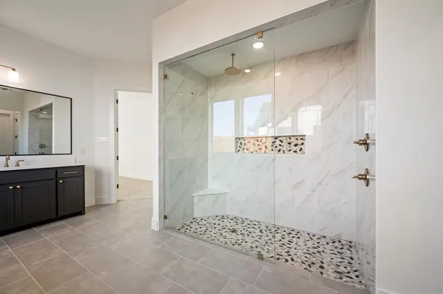 a bathroom with a granite countertop sink a mirror a shower and vanity
