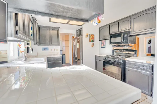 a kitchen with stainless steel appliances kitchen island granite countertop a refrigerator oven a sink dishwasher and white cabinets with wooden floor