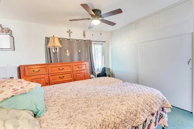 a bedroom with a bed dresser and two windows