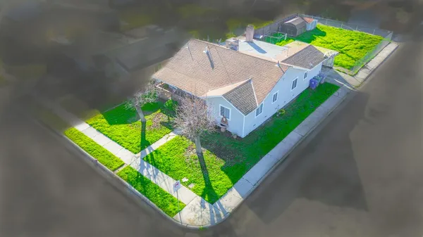 a view of a house with a big yard plants and large tree
