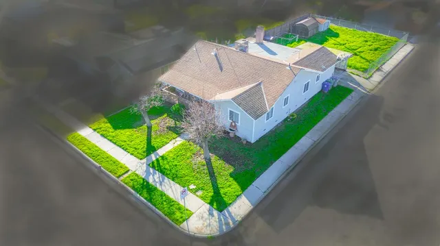 a view of a house with a big yard plants and large tree