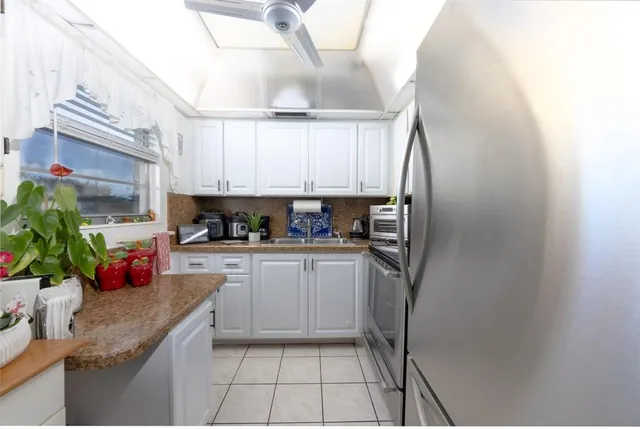 a kitchen with stainless steel appliances granite countertop a refrigerator sink and white cabinets