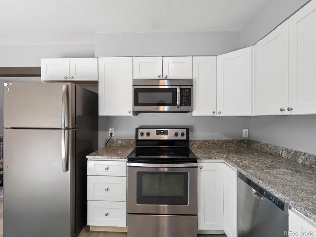 a kitchen with granite countertop white cabinets and a stove