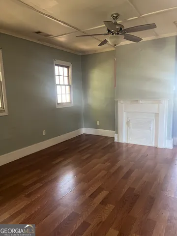 a view of an empty room with wooden floor and a window