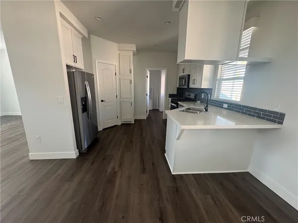 a hallway view with wooden floor and electronic appliances