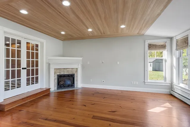 an empty room with wooden floor and a fireplace