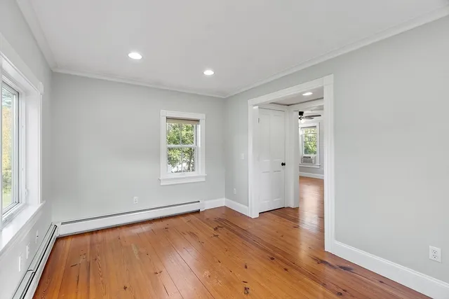 an empty room with wooden floor and windows