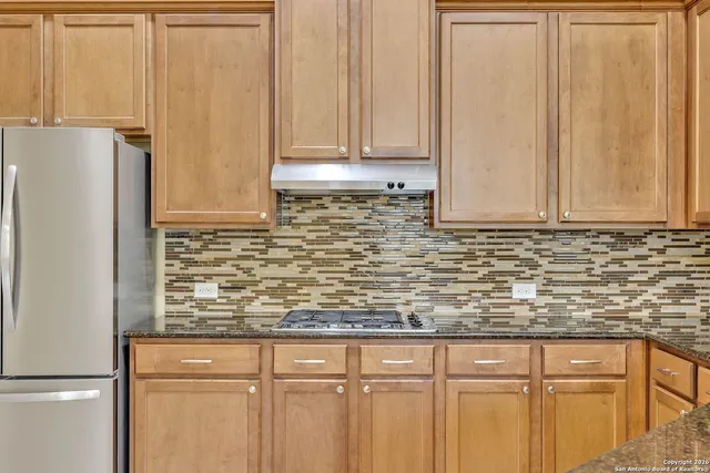 a view of kitchen with granite countertop cabinets and a refrigerator