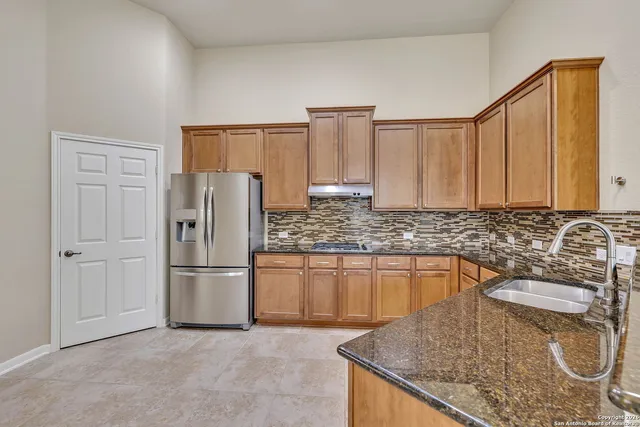 a kitchen with granite countertop a sink a stove and refrigerator