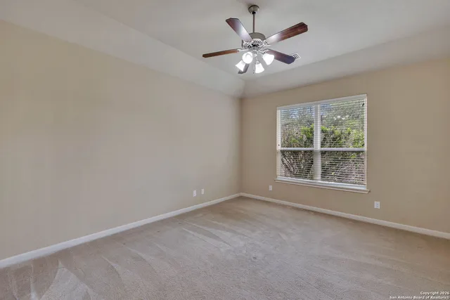 an empty room with a chandelier fan and windows