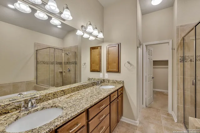 a bathroom with a granite countertop sink a large mirror and a shower