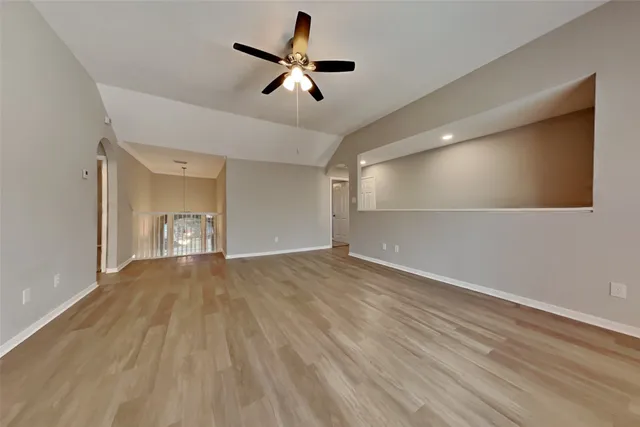 a view of empty room with wooden floor and ceiling fan