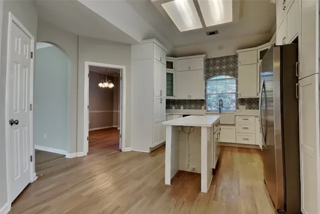 a kitchen with white cabinets and wooden floor