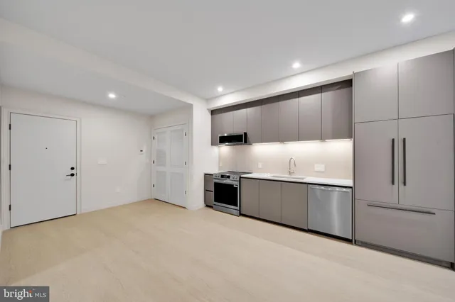 a large kitchen with stainless steel appliances granite countertop a refrigerator and a sink