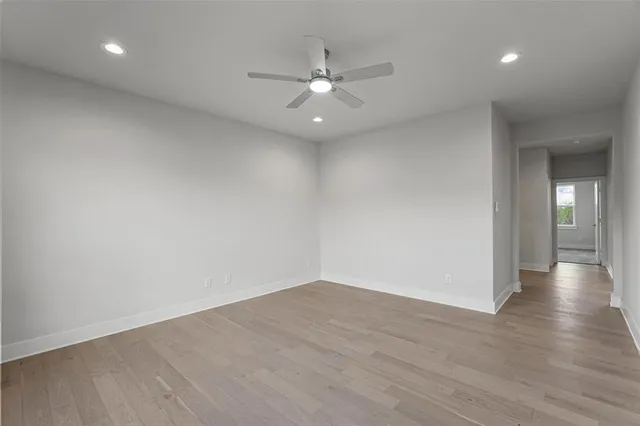 an empty room with wooden floor and fan
