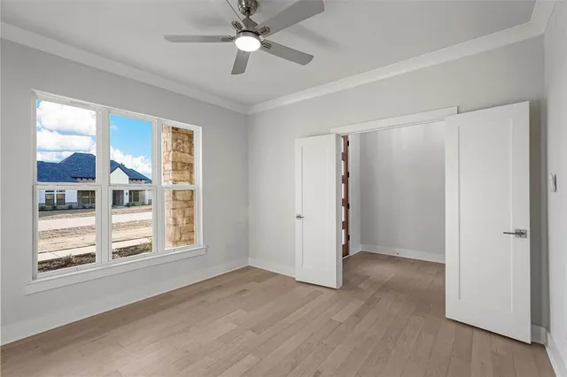 a view of an empty room with a window and wooden floor