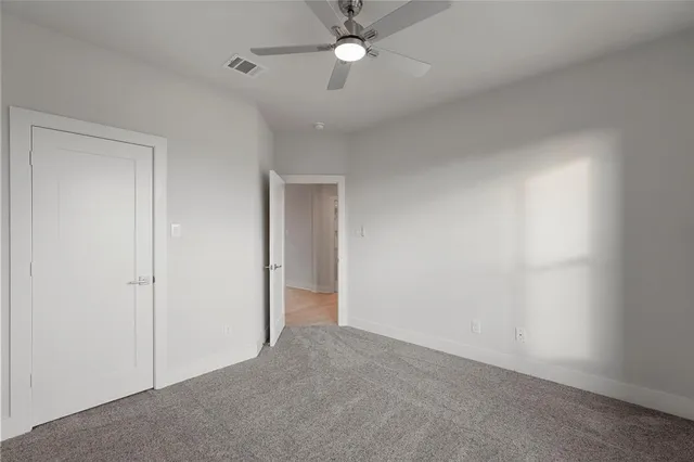 an empty room with closet and a chandelier fan