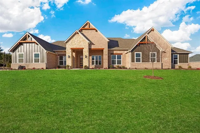 a front view of a house with a garden and trees