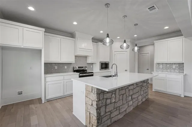 a kitchen with a sink a stove cabinets and wooden floor
