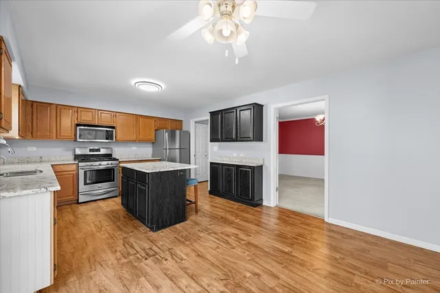 a large kitchen with a stove top oven a sink dishwasher a dining table and chairs with wooden floor