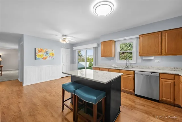a kitchen with stainless steel appliances granite countertop a sink dishwasher a stove and a refrigerator with wooden floor