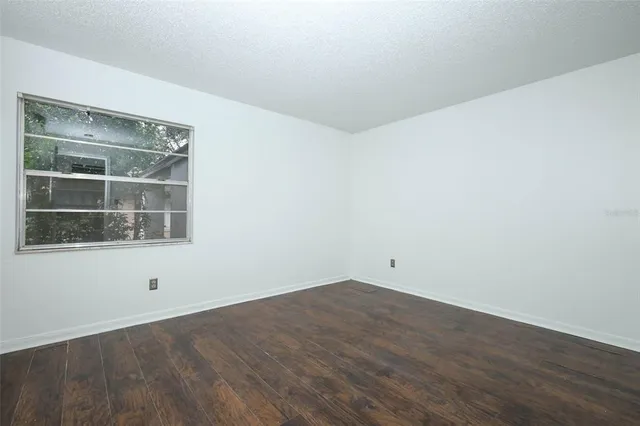 a view of an empty room with wooden floor and windows