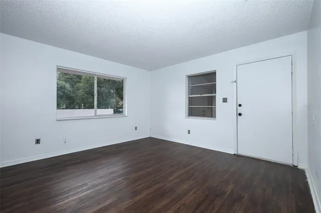 a view of empty room with wooden floor and windows