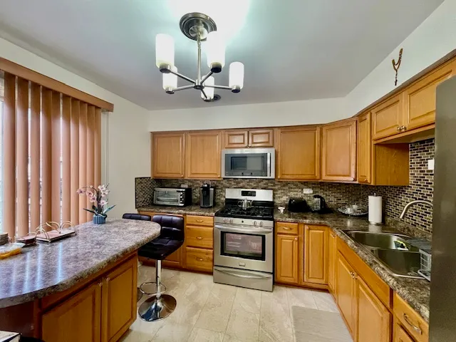 a kitchen with stainless steel appliances granite countertop a sink a stove and a refrigerator