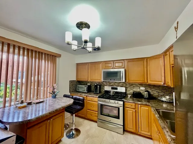 a kitchen with stainless steel appliances granite countertop a stove a sink dishwasher and a microwave with wooden floor