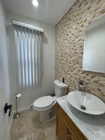 a bathroom with a granite countertop toilet a sink and a mirror