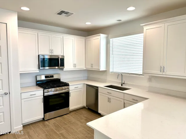 a kitchen with stainless steel appliances granite countertop a sink a stove a microwave a sink and cabinets