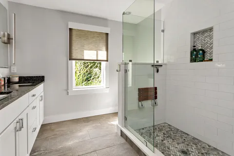 a bathroom with a granite countertop sink a window and shower