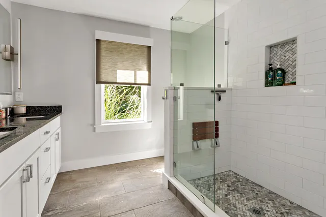 a bathroom with a granite countertop sink a window and shower